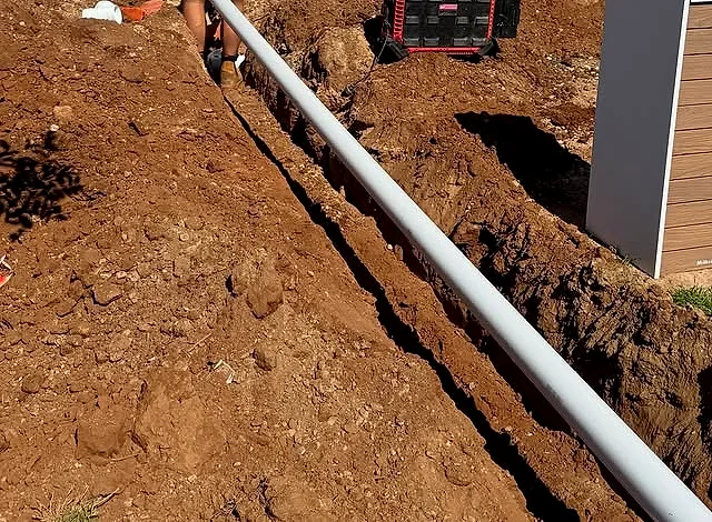 New stormwater pipe being installed in a trench beside a new build